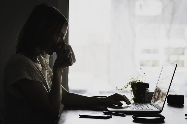 woman drinking coffee browsing on laptop